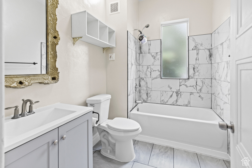 Full bathroom with tiled shower / bath combo, tile patterned flooring, toilet, and vanity