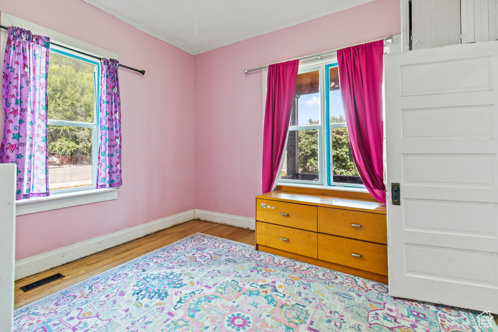 Bedroom with light hardwood / wood-style flooring and multiple windows