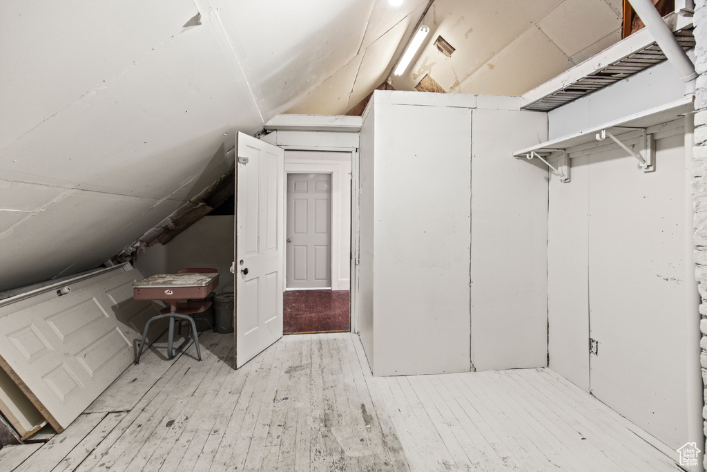 Bonus room with light wood-type flooring and vaulted ceiling