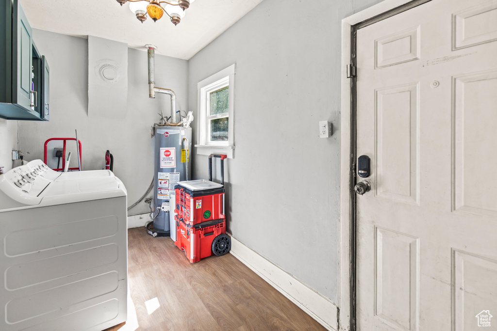 Washroom with water heater, light hardwood / wood-style floors, separate washer and dryer, and cabinets