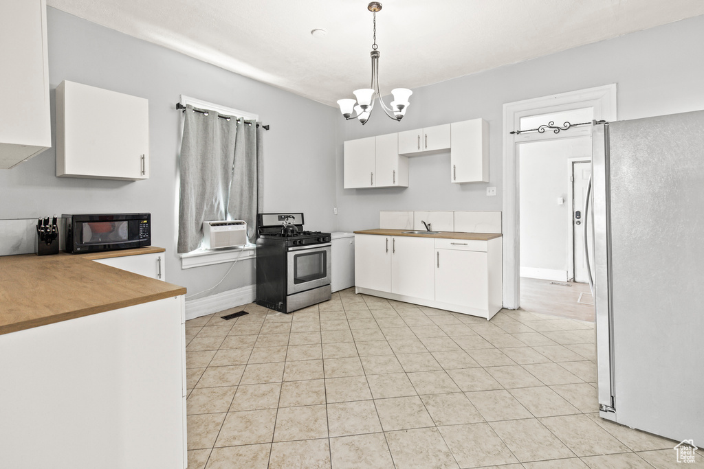 Kitchen featuring a chandelier, gas stove, pendant lighting, light tile patterned flooring, and white refrigerator