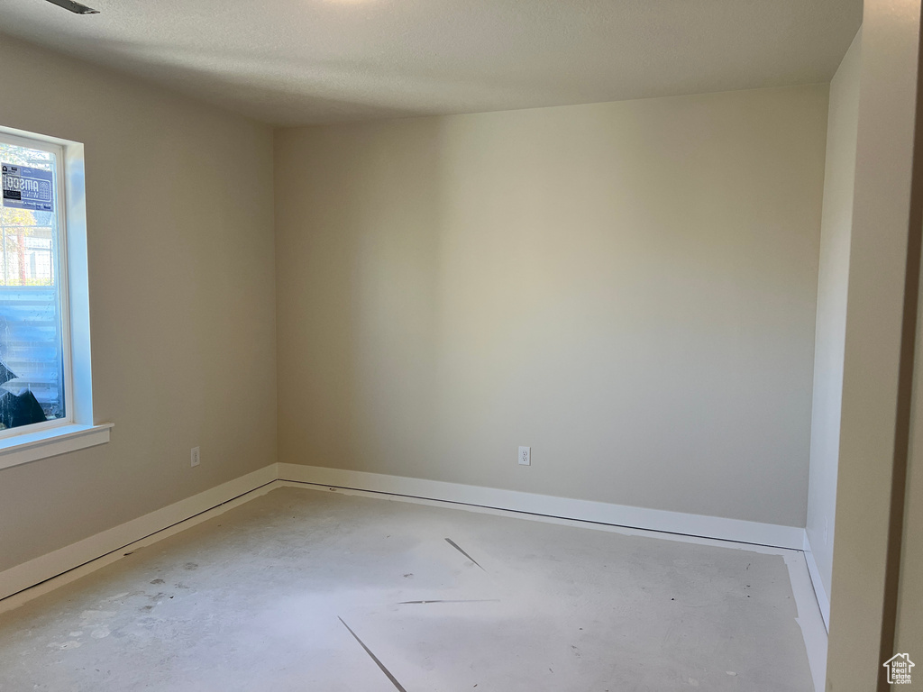 Unfurnished room with concrete flooring and a textured ceiling