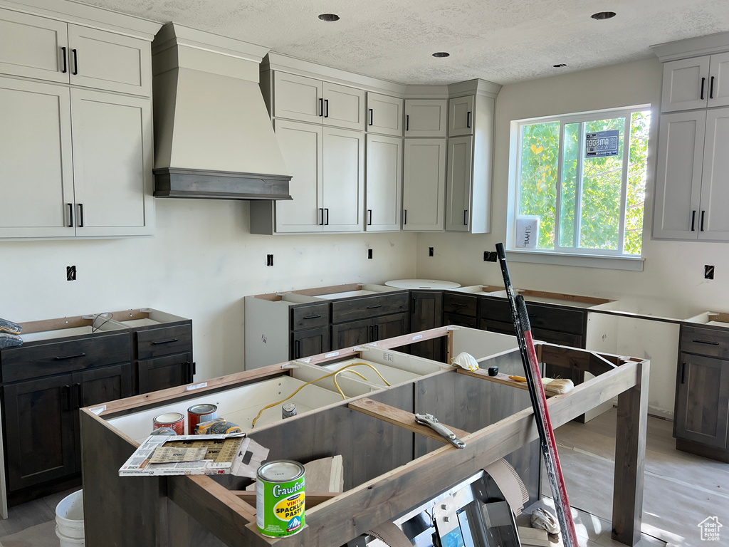 Kitchen with gray cabinets, premium range hood, and a textured ceiling