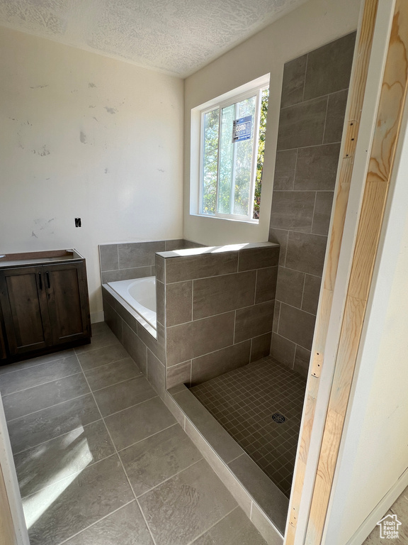 Bathroom featuring shower with separate bathtub, tile patterned flooring, and a textured ceiling