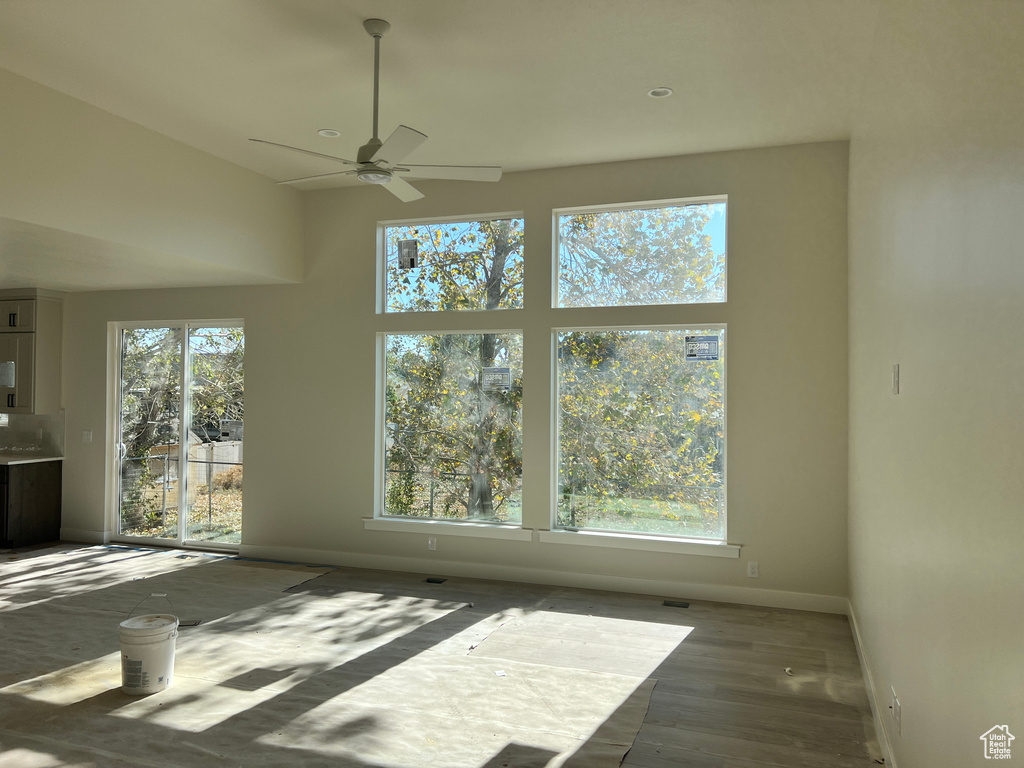 Empty room featuring dark wood-type flooring, a healthy amount of sunlight, and ceiling fan