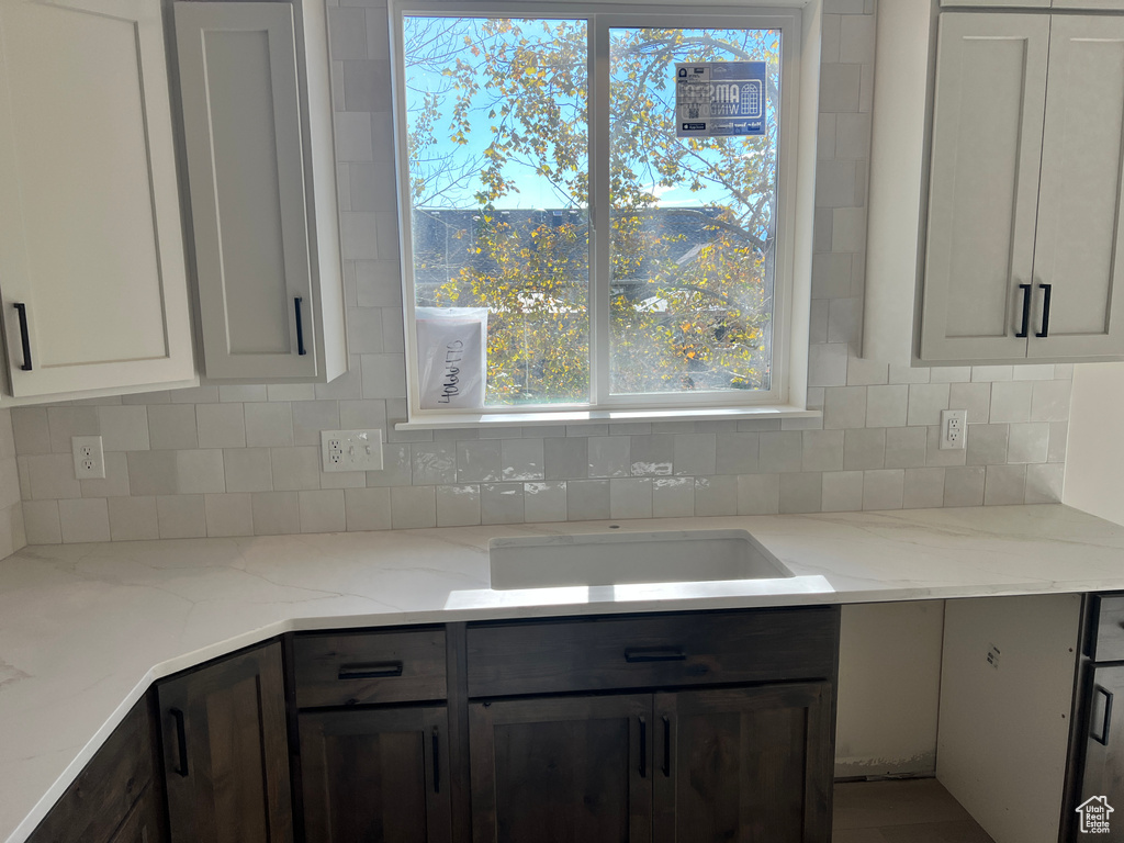 Kitchen featuring light stone counters, tasteful backsplash, dark brown cabinets, a mountain view, and white cabinetry