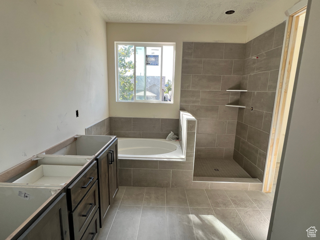 Bathroom with tile patterned floors, shower with separate bathtub, vanity, and a textured ceiling