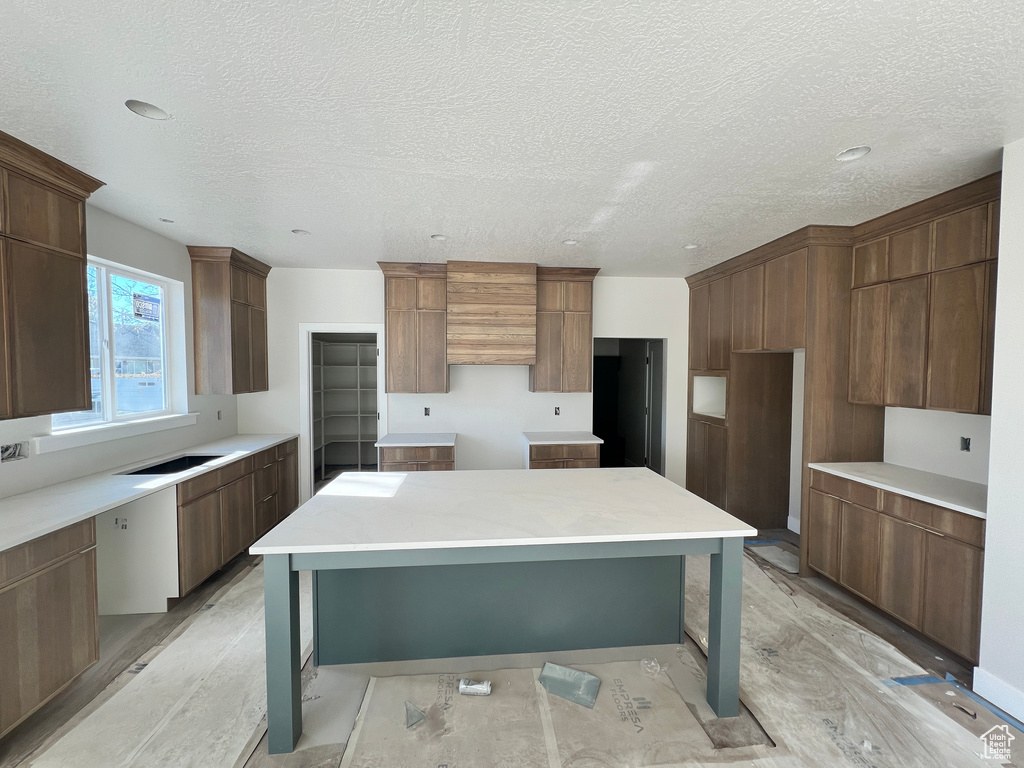 Kitchen featuring a textured ceiling, light hardwood / wood-style flooring, and a center island