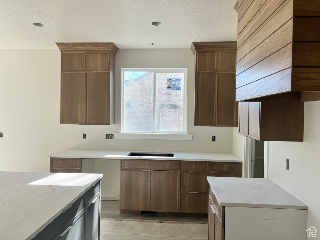 Kitchen with refrigerator, custom range hood, and a textured ceiling