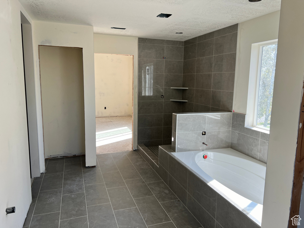 Bathroom featuring separate shower and tub, tile patterned flooring, and a textured ceiling