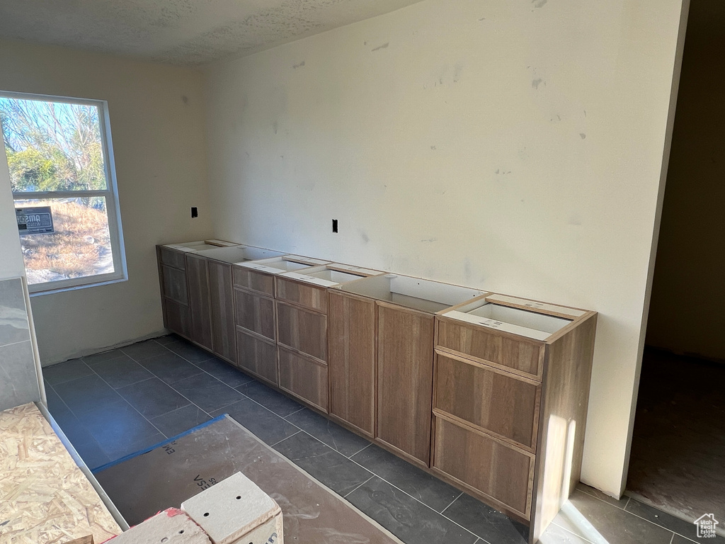 Kitchen featuring a textured ceiling and dark tile patterned flooring