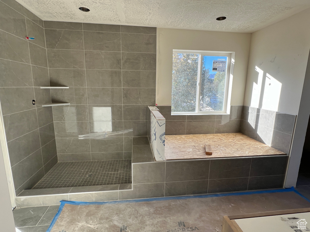 Bathroom with a tile shower and a textured ceiling