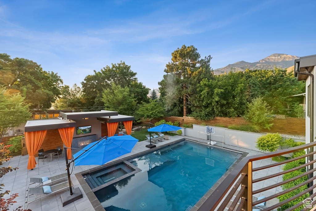 View of pool with an in ground hot tub and a mountain view