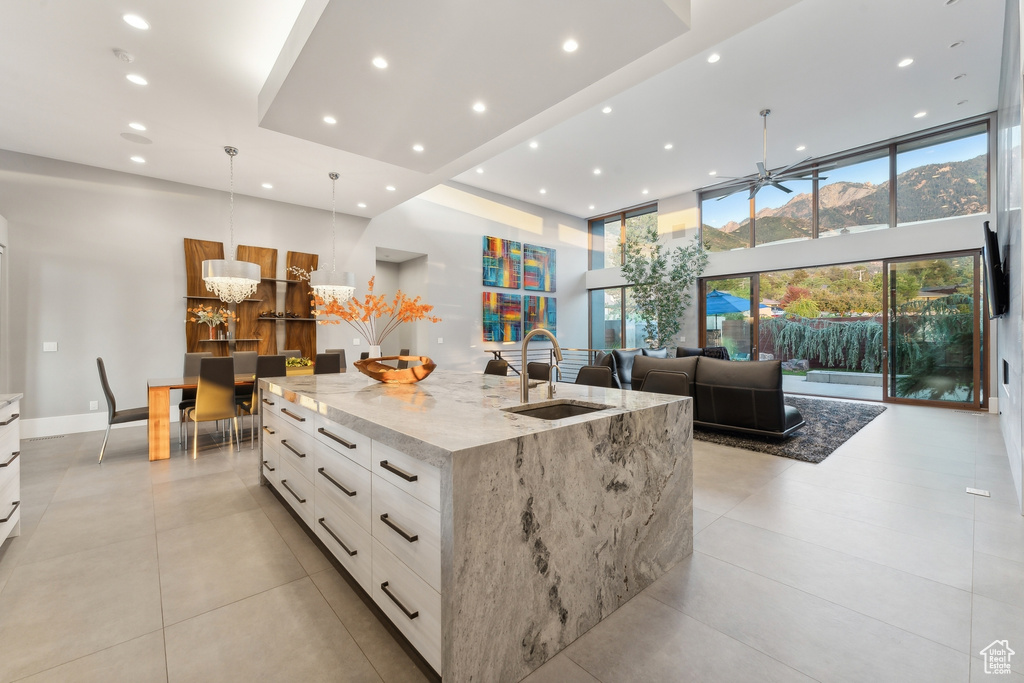 Kitchen with pendant lighting, a large island, light stone counters, light tile patterned floors, and sink