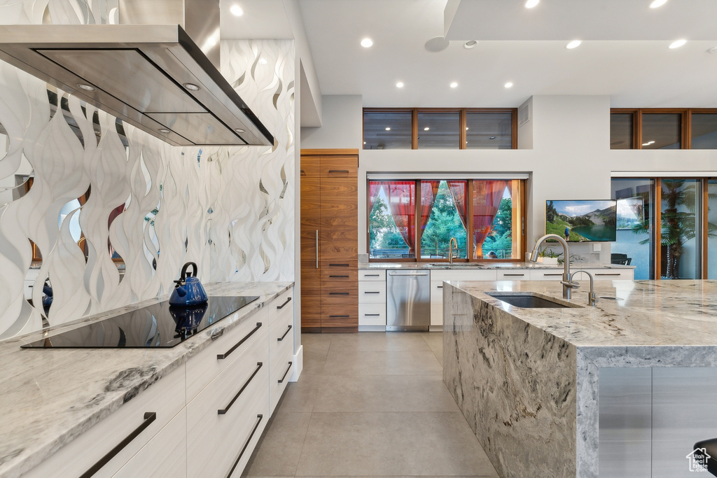 Kitchen featuring stainless steel dishwasher, light stone counters, black electric cooktop, sink, and light tile patterned flooring