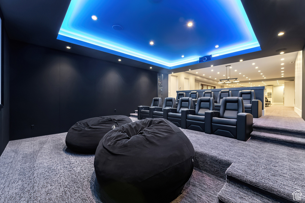 Carpeted home theater featuring a tray ceiling