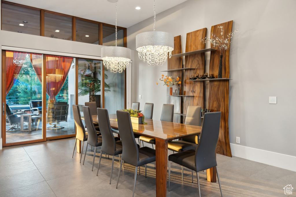 Tiled dining room featuring a notable chandelier and a towering ceiling