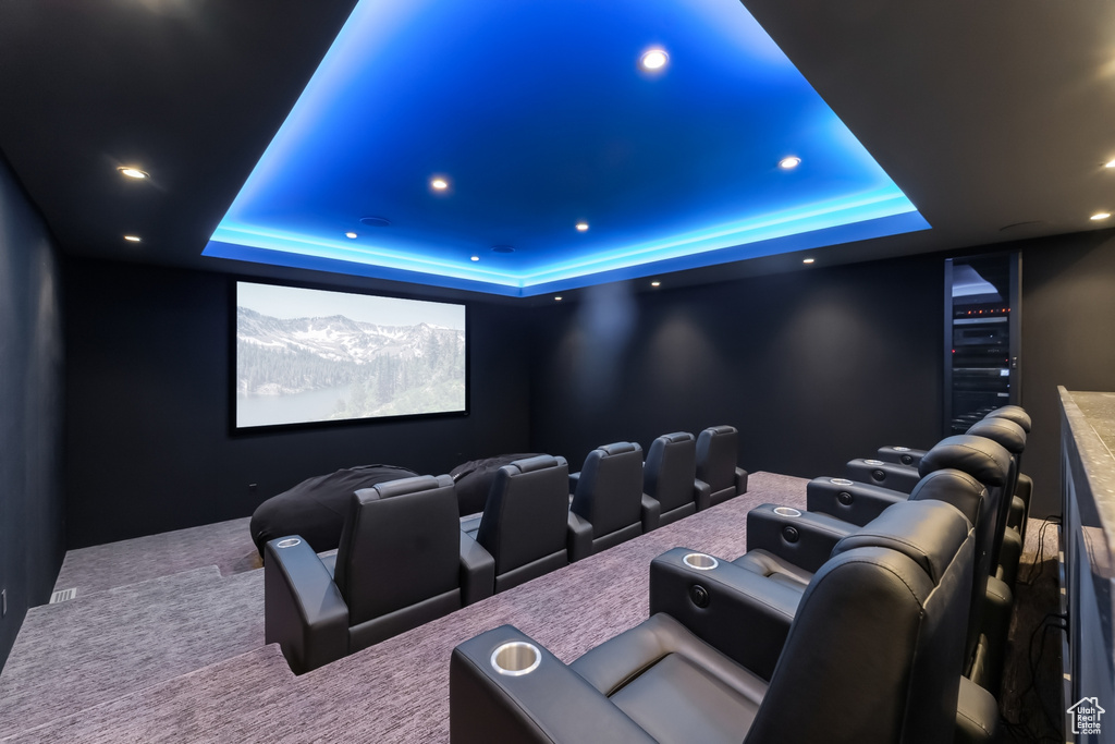 Carpeted cinema room with a raised ceiling