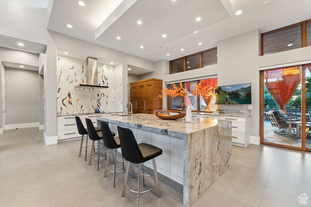 Kitchen featuring white cabinetry, a spacious island, and wall chimney exhaust hood