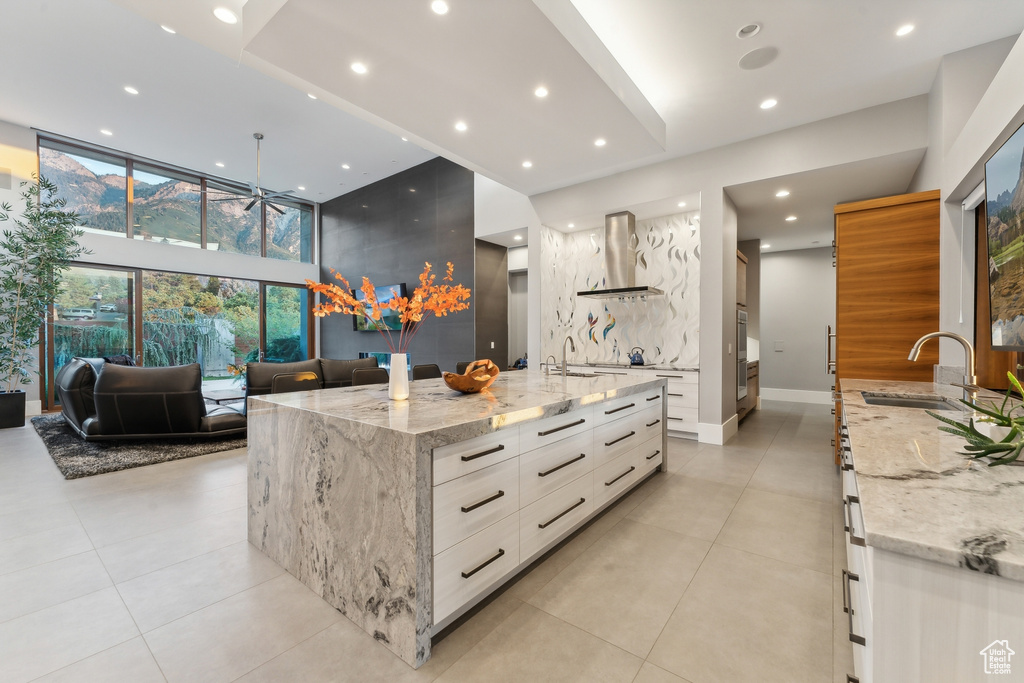 Kitchen with light tile patterned flooring, extractor fan, a spacious island, and light stone countertops