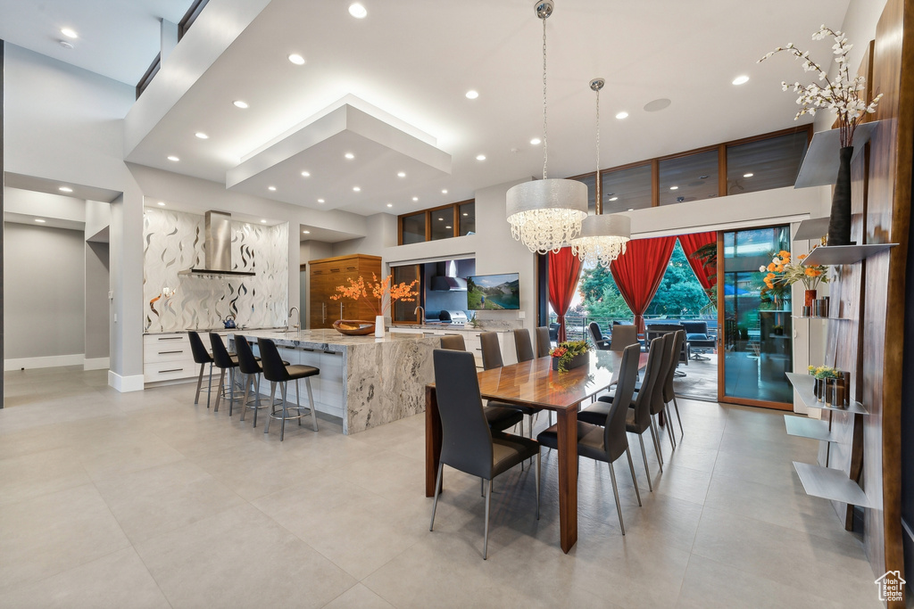 Dining area with sink, a high ceiling, a chandelier, and light tile patterned floors