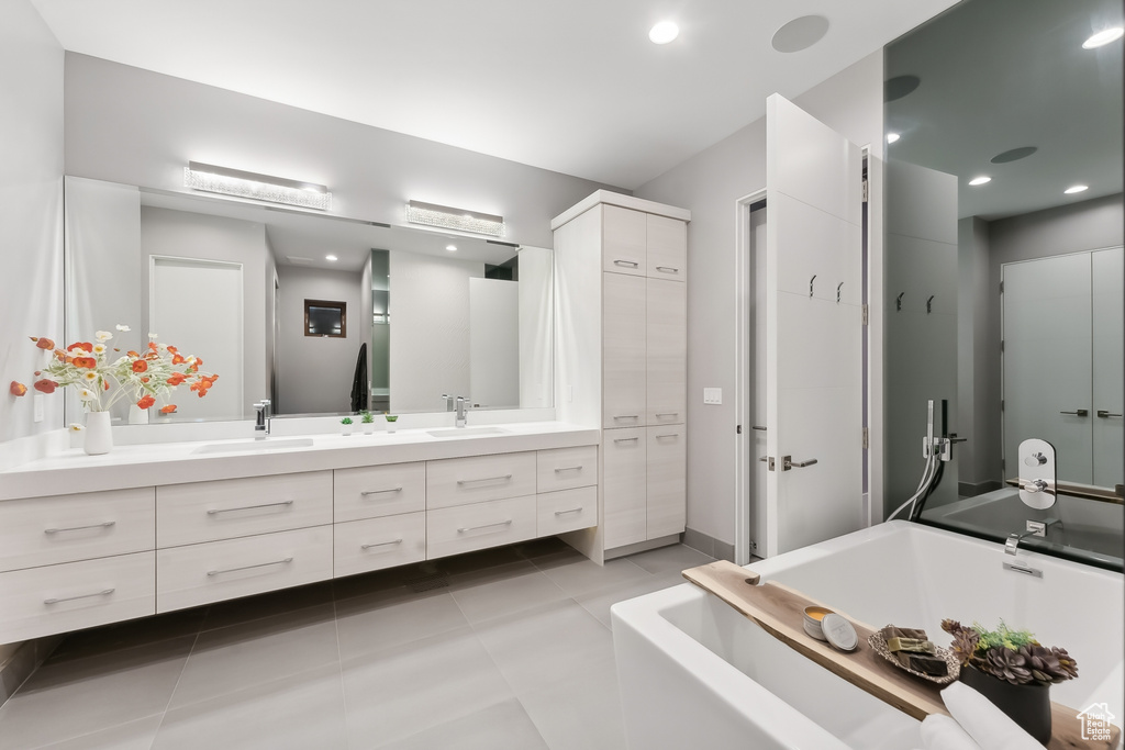 Bathroom featuring double vanity, a tub to relax in, and tile patterned floors