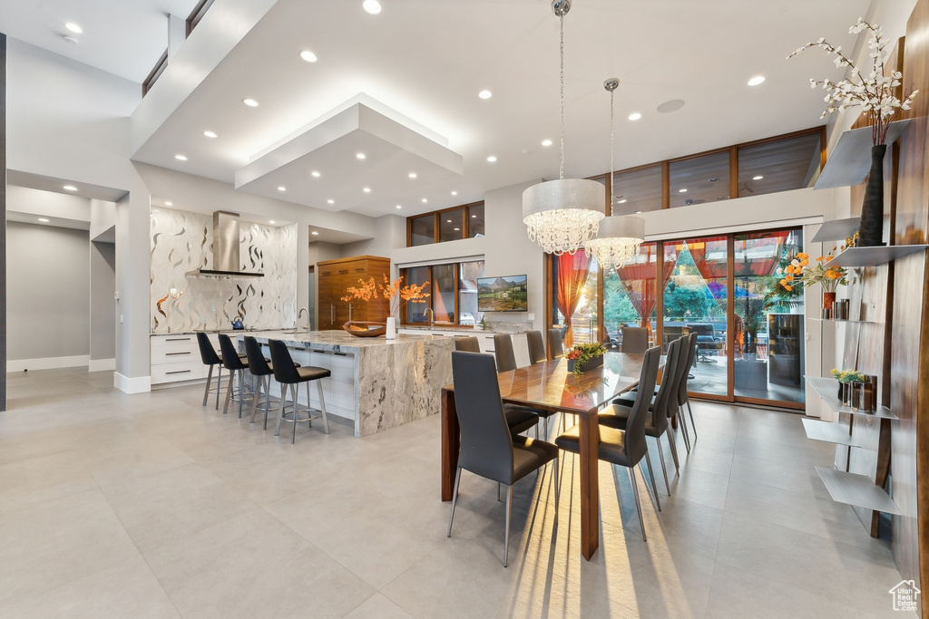 Tiled dining area with a high ceiling, sink, and an inviting chandelier