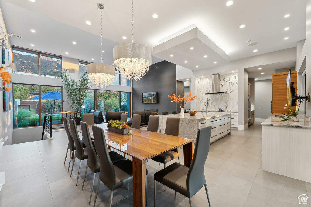 Tiled dining space featuring sink, plenty of natural light, and a notable chandelier