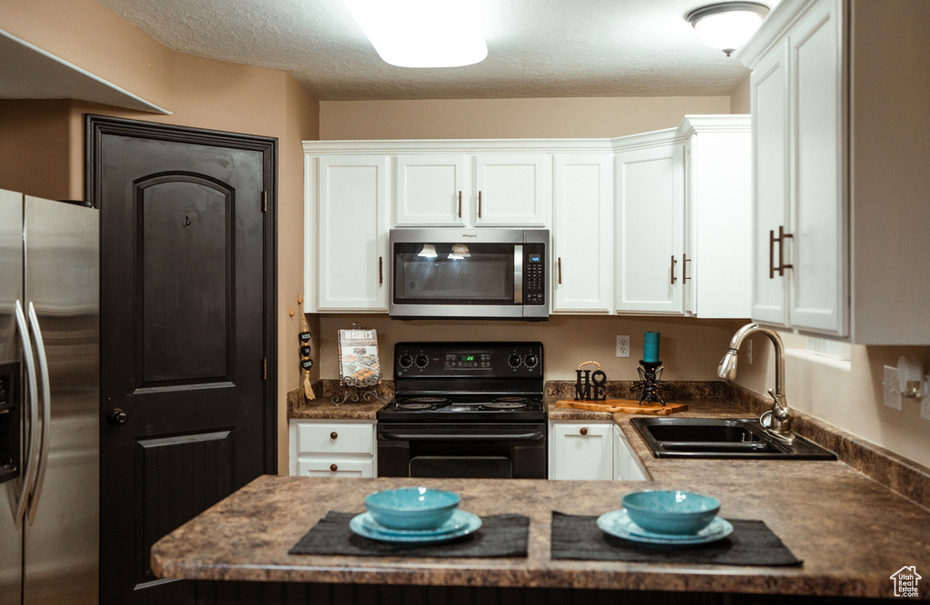 Kitchen featuring white cabinets, stainless steel appliances, a textured ceiling, and sink