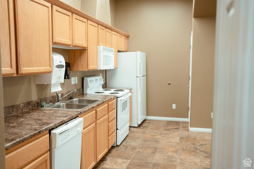 Kitchen featuring sink, white appliances, light brown cabinetry, and light tile patterned floors