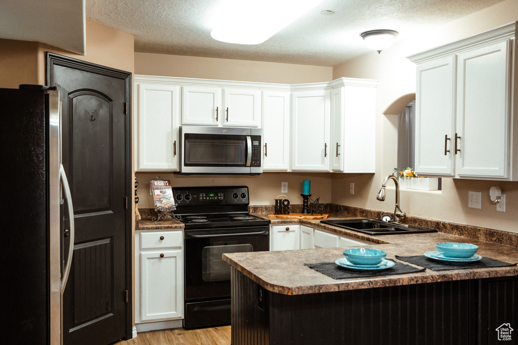 Kitchen featuring light wood-type flooring, appliances with stainless steel finishes, kitchen peninsula, and sink