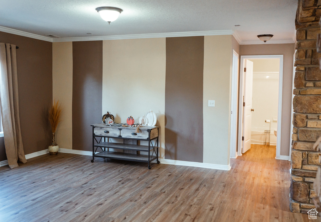 Empty room featuring wood-type flooring, a textured ceiling, and ornamental molding