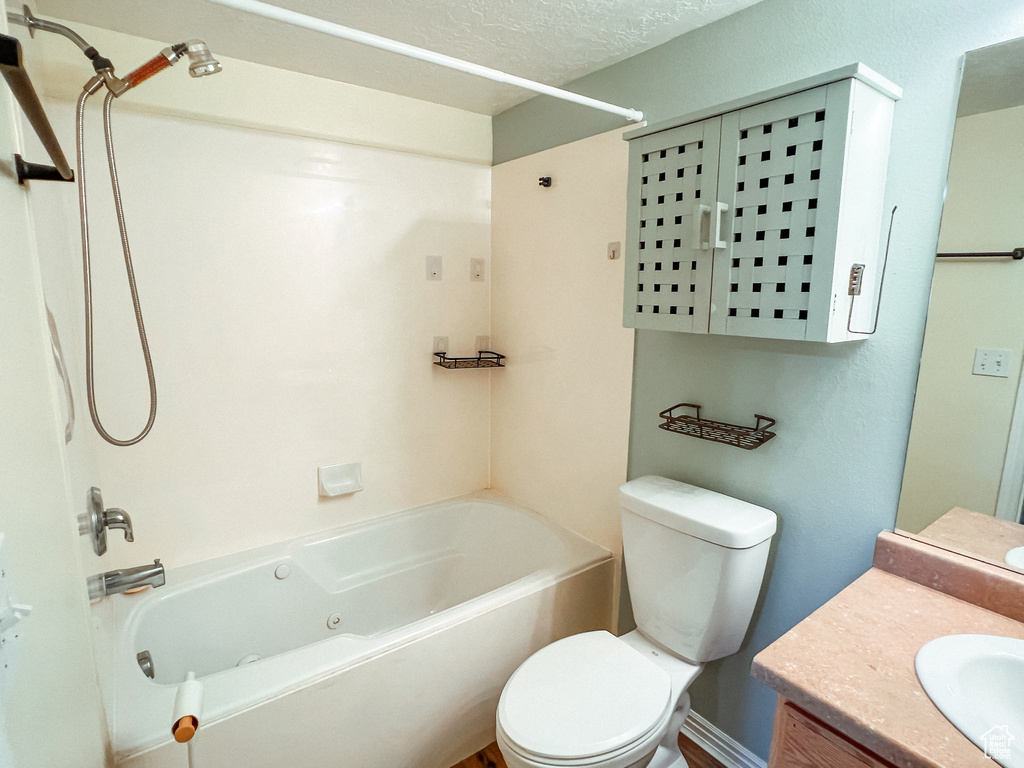 Full bathroom with vanity, toilet, a textured ceiling, and bathing tub / shower combination