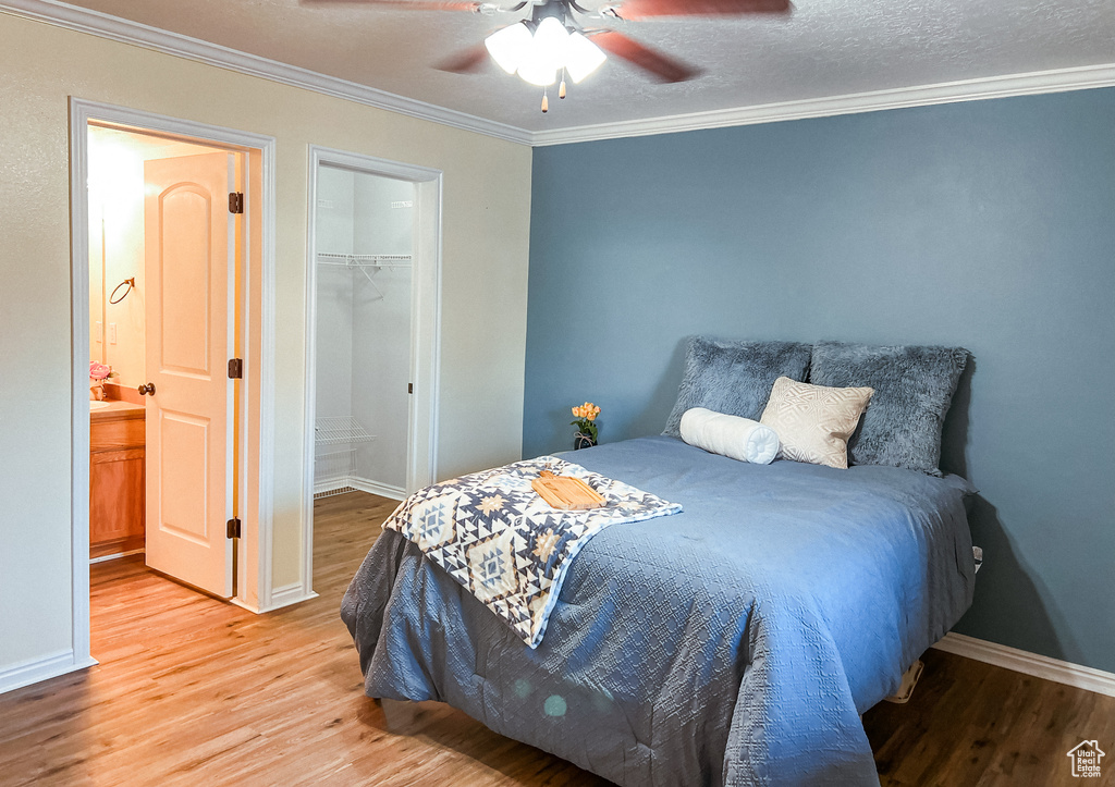 Bedroom featuring a closet, wood-type flooring, a spacious closet, ceiling fan, and a textured ceiling