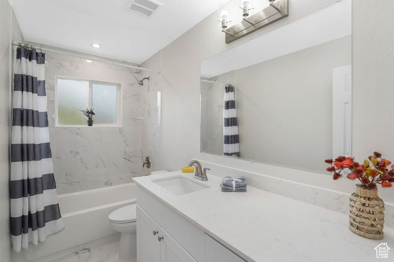 Full bathroom with toilet, vanity, shower / bath combo with shower curtain, and tile patterned floors