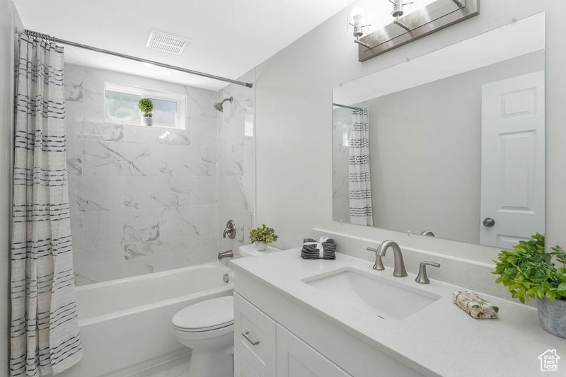 Full bathroom featuring vanity, shower / bathtub combination with curtain, and toilet