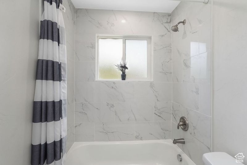 Bathroom featuring toilet and shower / bath combo with shower curtain