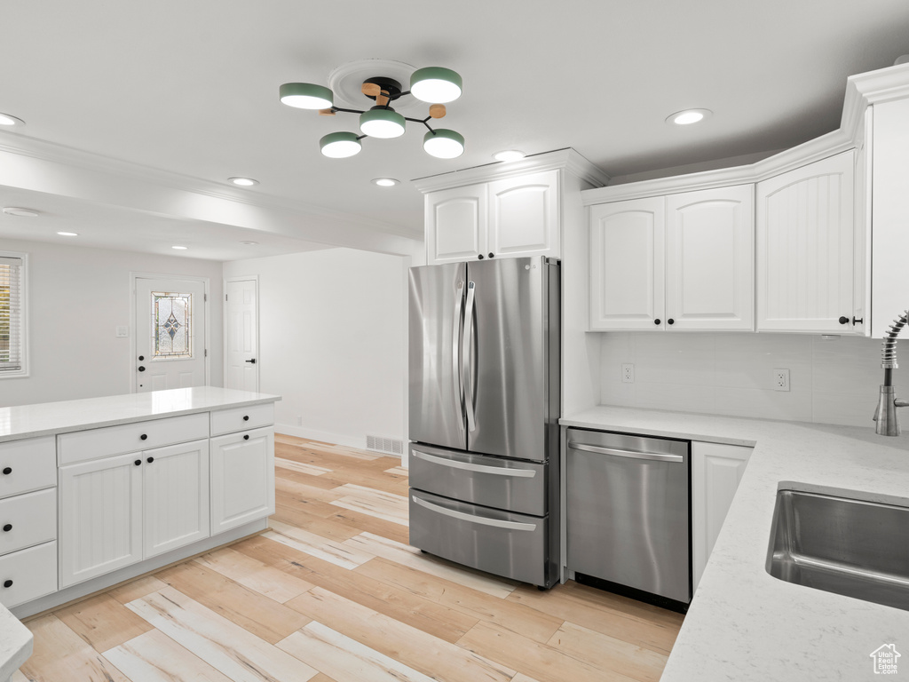 Kitchen with light wood-type flooring, appliances with stainless steel finishes, sink, and white cabinetry