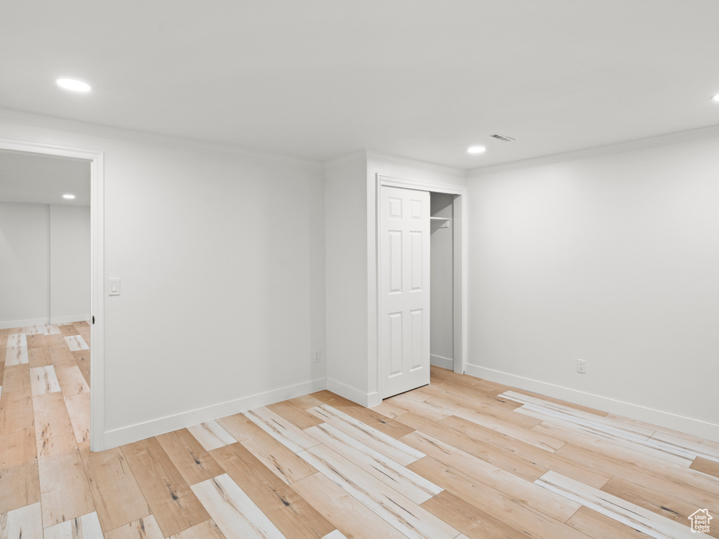 Unfurnished bedroom featuring light hardwood / wood-style flooring, crown molding, and a closet