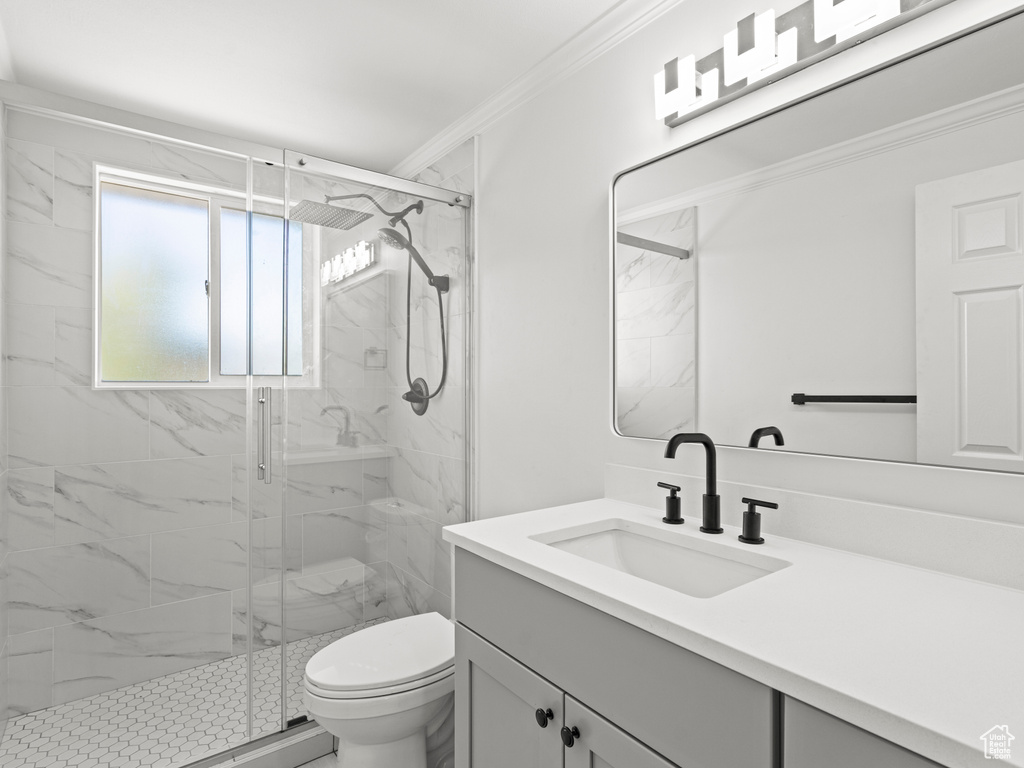 Bathroom featuring toilet, a shower with shower door, vanity, and ornamental molding