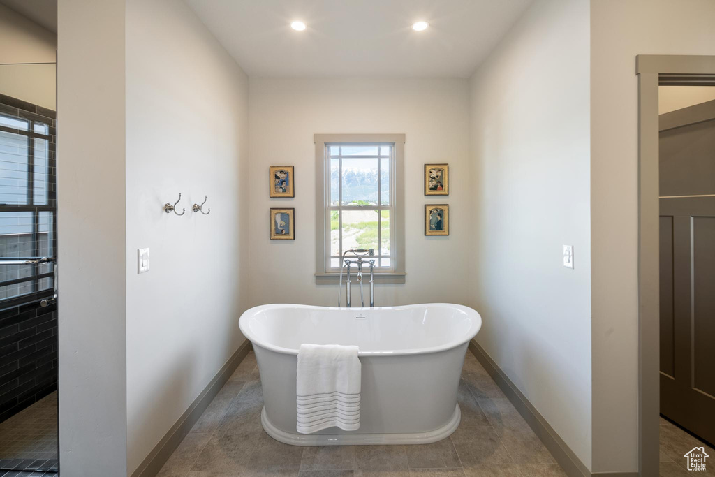 Bathroom with tile patterned flooring and a washtub