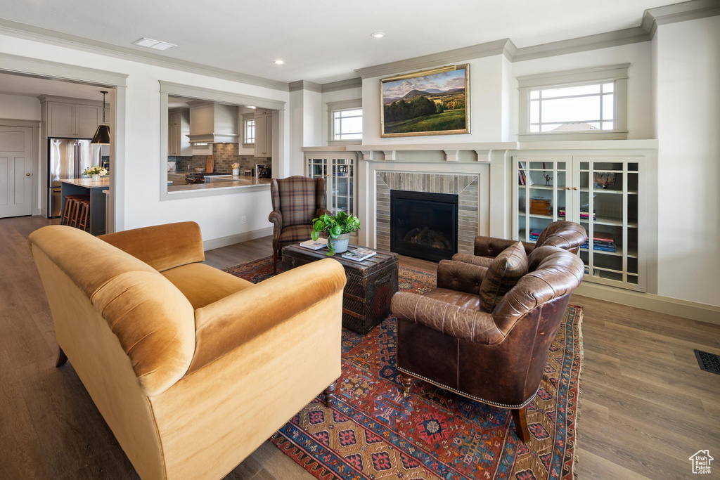 Living room featuring ornamental molding, hardwood / wood-style flooring, and a brick fireplace