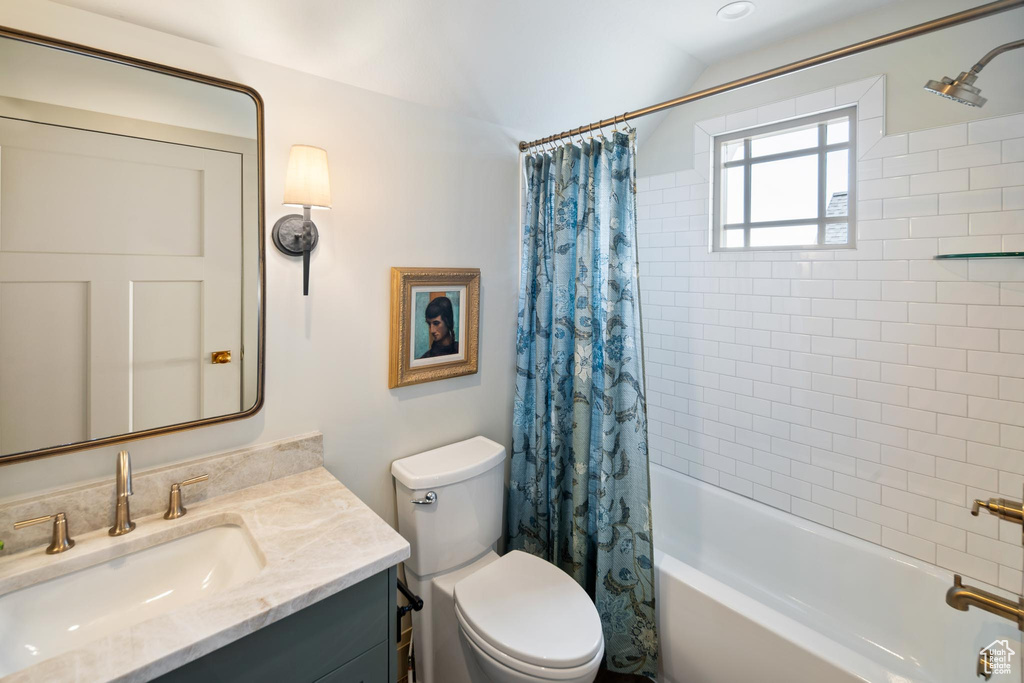 Full bathroom featuring toilet, shower / tub combo with curtain, and vanity