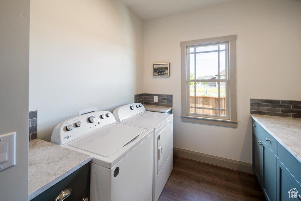 Laundry area with washing machine and dryer, dark hardwood / wood-style floors, and cabinets