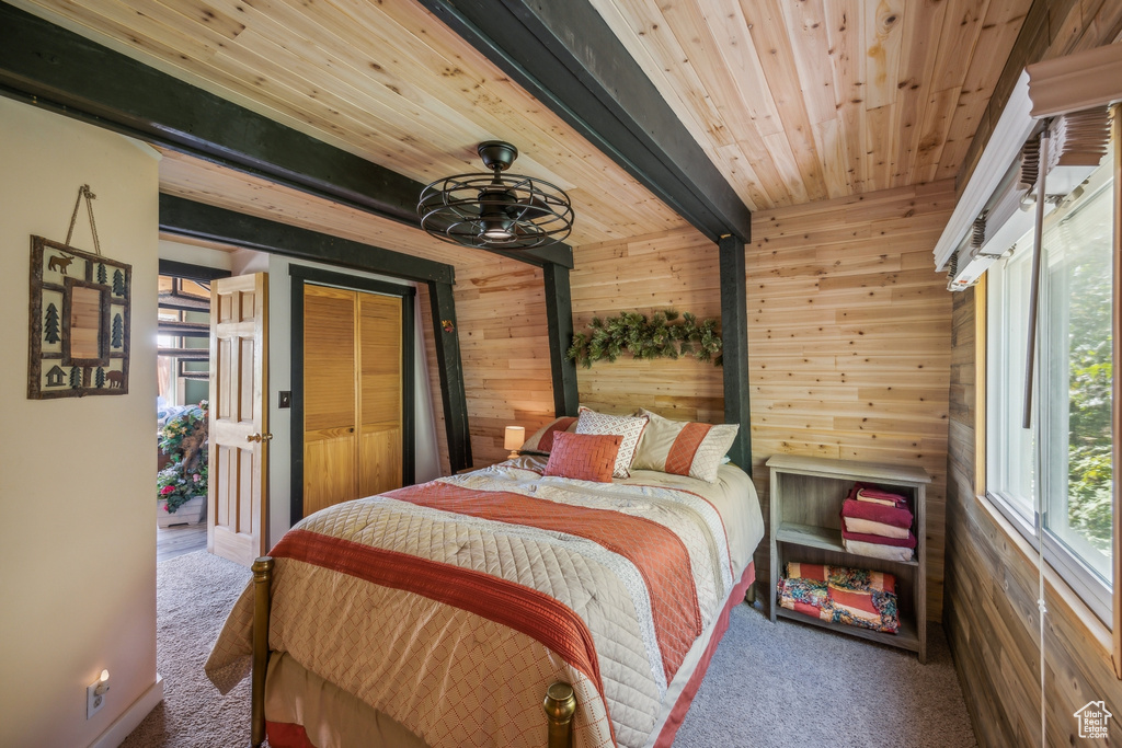 Carpeted bedroom featuring wood walls, wooden ceiling, and beamed ceiling