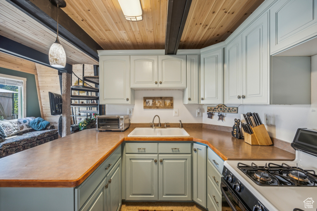 Kitchen with wood ceiling, gas stove, sink, decorative light fixtures, and beamed ceiling