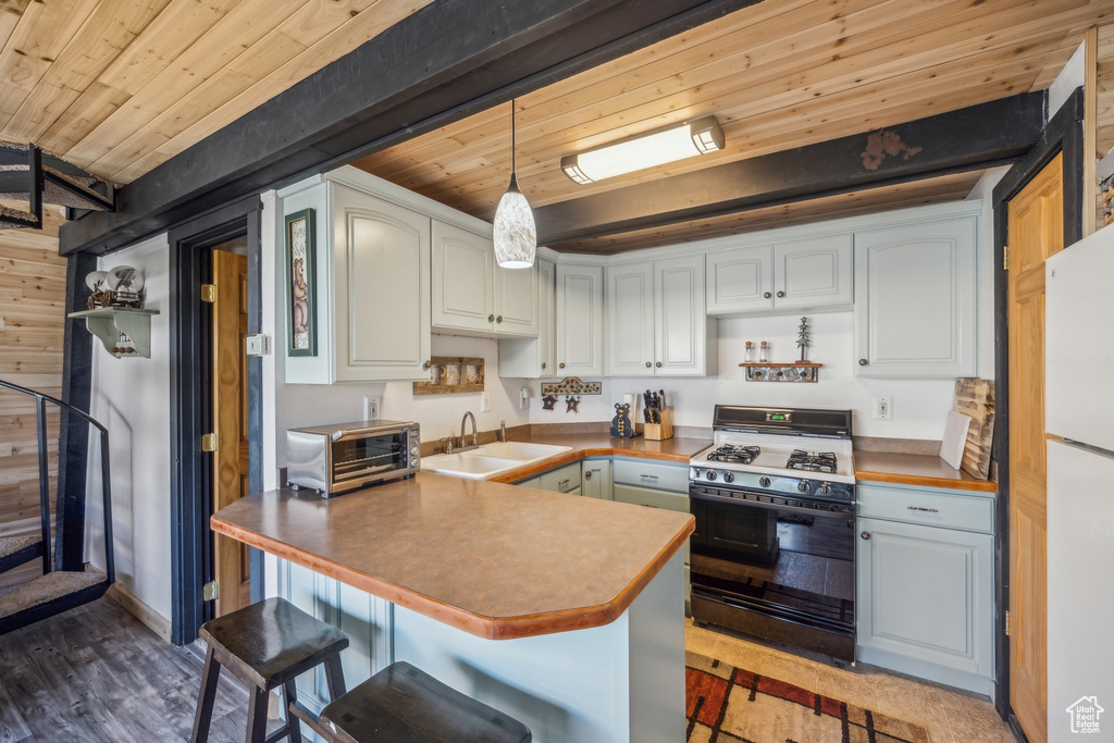 Kitchen with pendant lighting, hardwood / wood-style floors, double oven range, sink, and a breakfast bar area