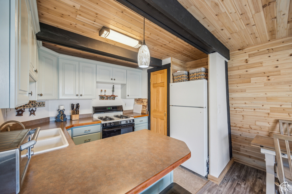 Kitchen featuring hardwood / wood-style floors, wooden walls, white appliances, and white cabinets