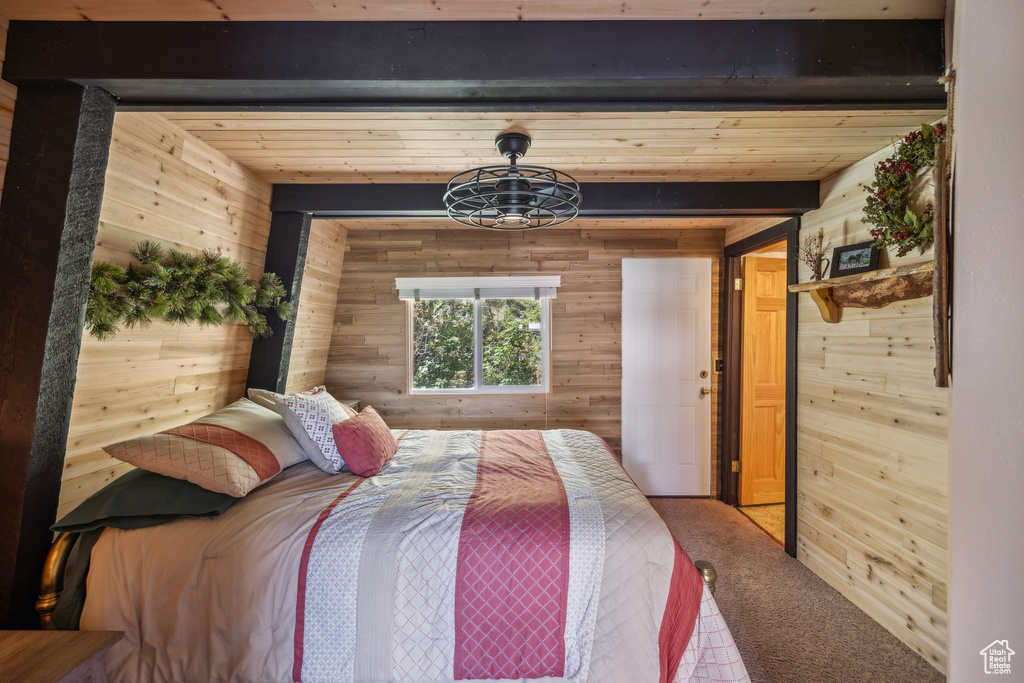 Bedroom with beam ceiling, wooden walls, and carpet flooring