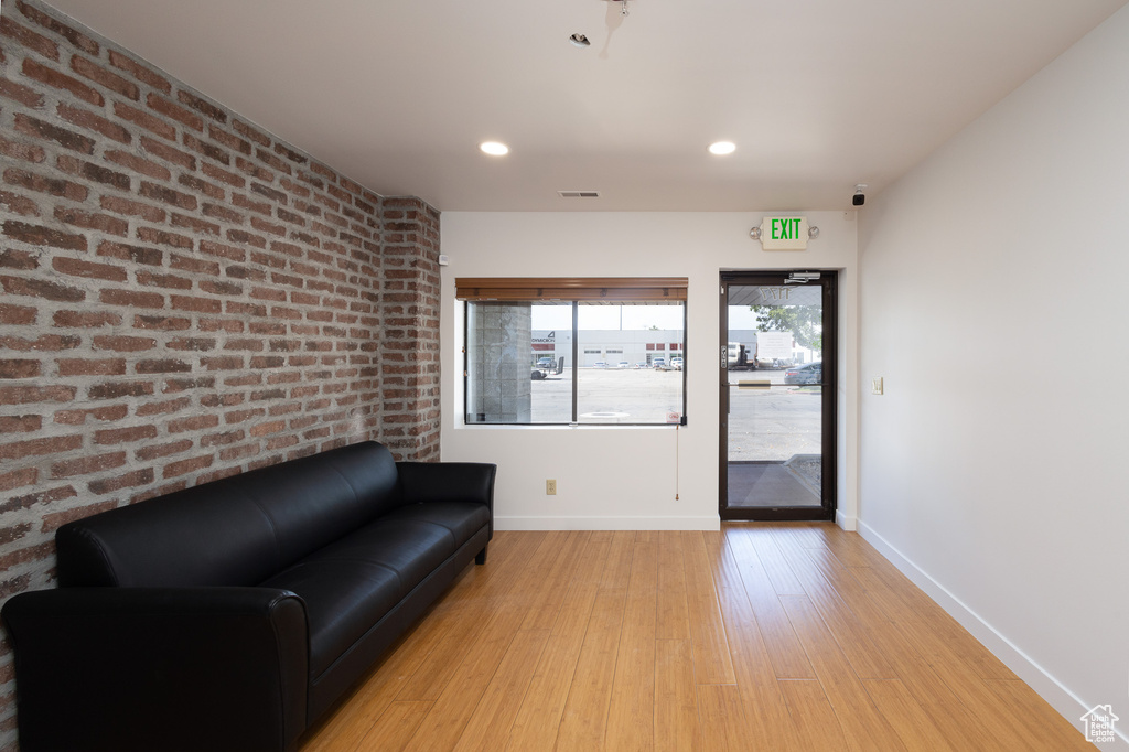 Living area featuring brick wall and light hardwood / wood-style floors